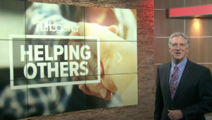 Screen reads "Helping others" behind a news anchor